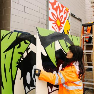 A worker installs an art piece at a light rail station.