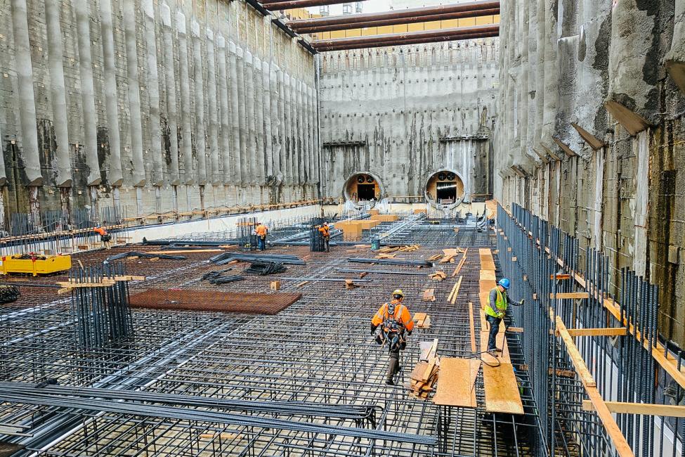 U District Station under construction in 2017 appears as a giant hole in the ground with a maze of steel bars across the bottom. It opens for service in 2021.