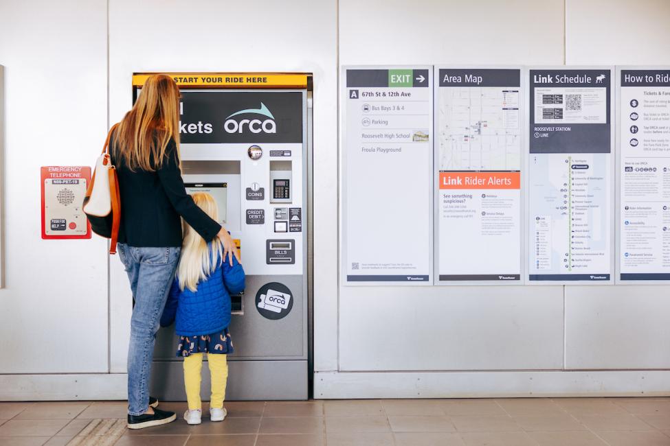 An adult and a young child using an ORCA ticket machine.