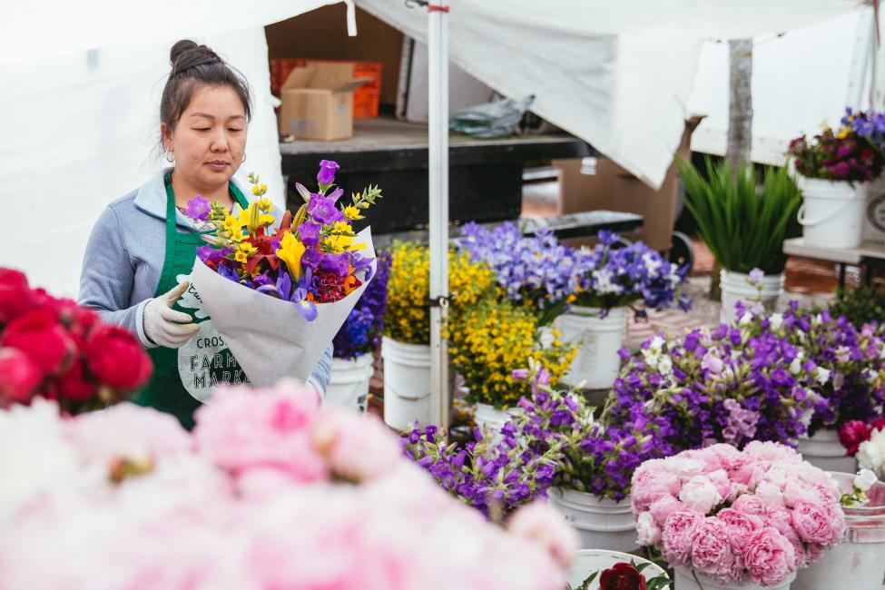 A flower vendor puts together bouquets at the Tacoma Farmers Market