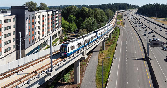 A light rail train travels along the freeway in Snohomish County.