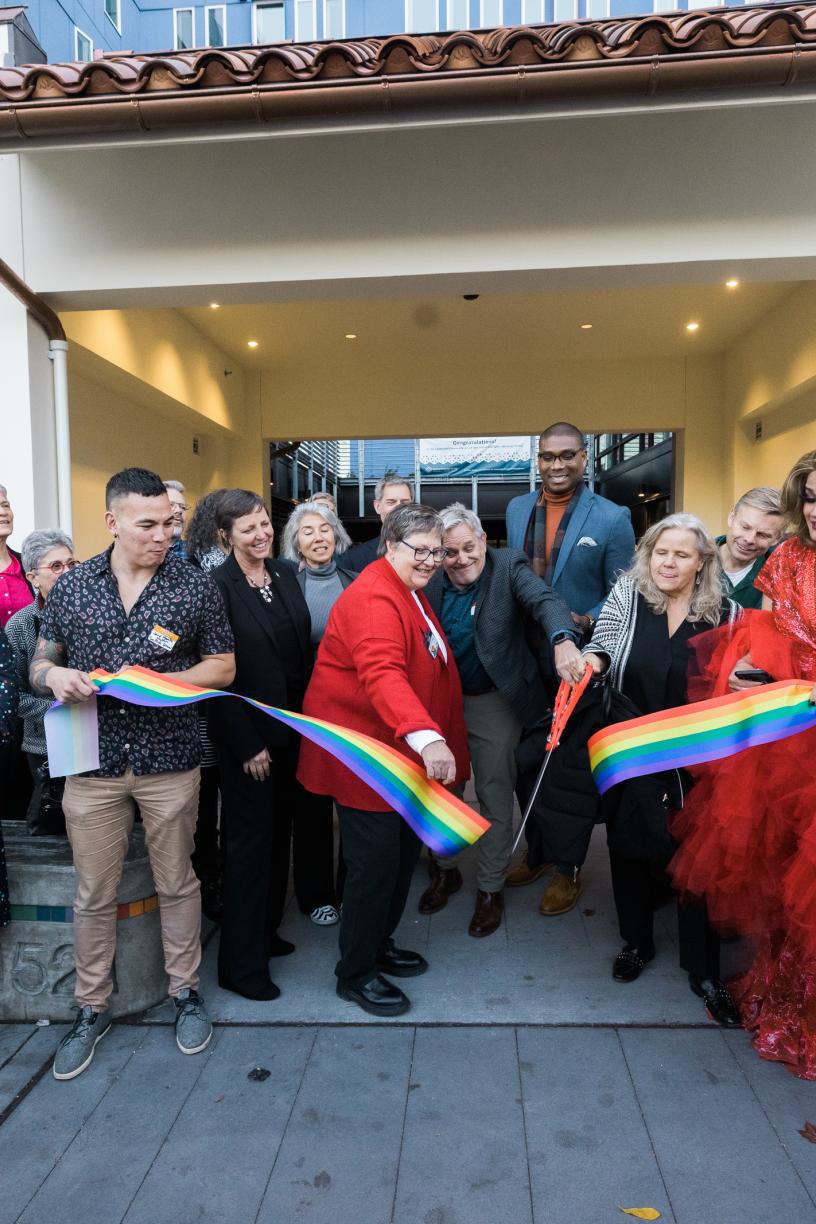 Image of a pride flag ribbon being cut by community members