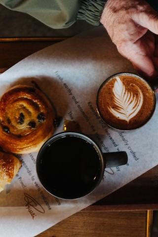 Pastries and mugs with black coffee and a latte on a tray