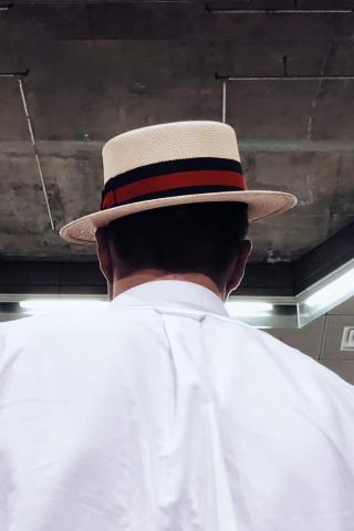 The back of a person's head as they sport a cool fedora while going up an escalator in a 1 Line station