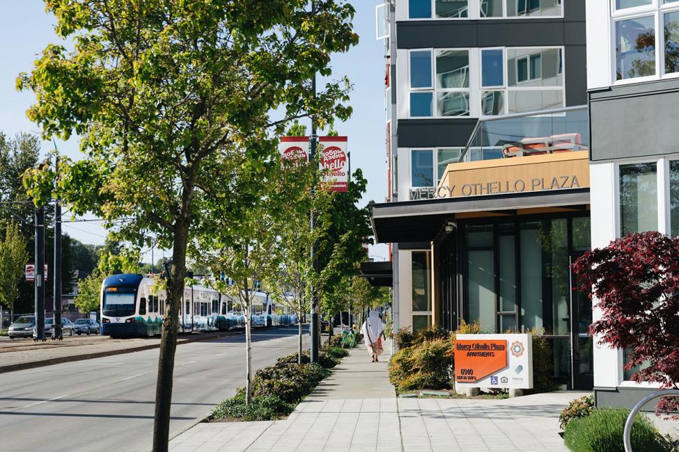 Mercy Othello Plaza at street level with a Link light rail train in the background.