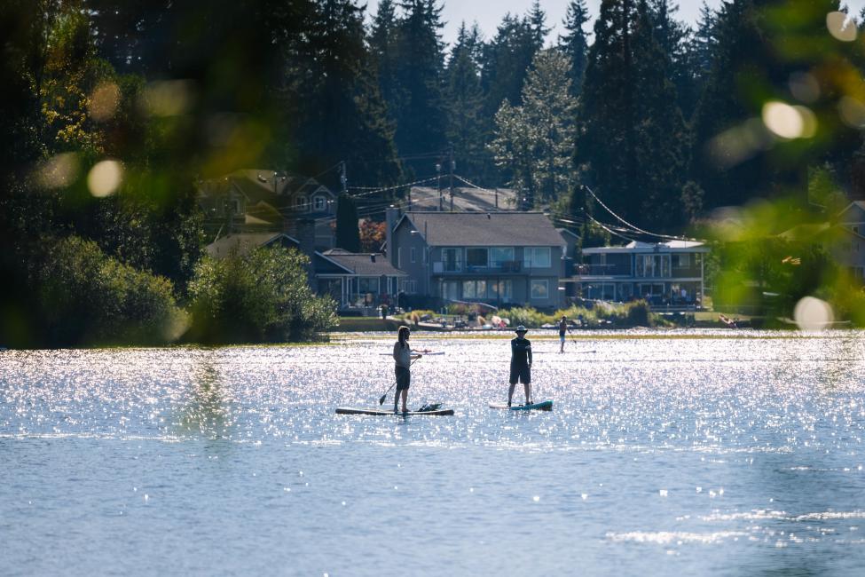 Two paddleboarders on Silver Lake as seen from the lake shore