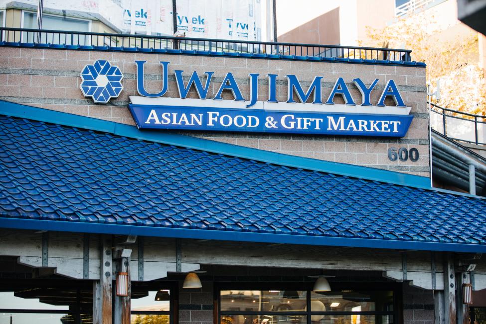 A blue sign on a building reads "Uwajimaya Asian Food and Gift Market"