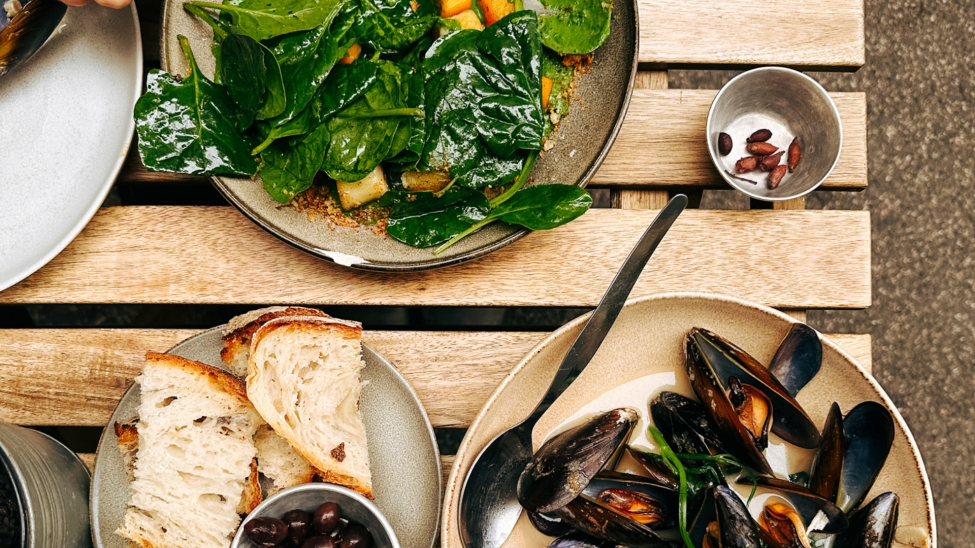 Looking down at a table with bread, mussels and salad 