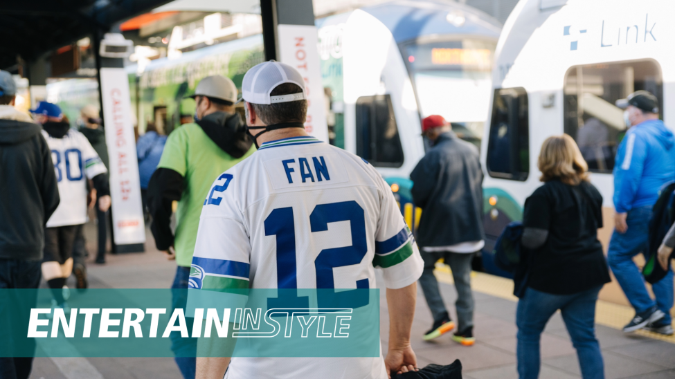 A Seahawks fan walks on a train platform surrounded by other people