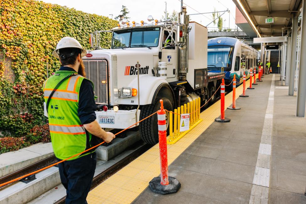 A large truck pulls a Link vehicle along tracks on Mercer Island