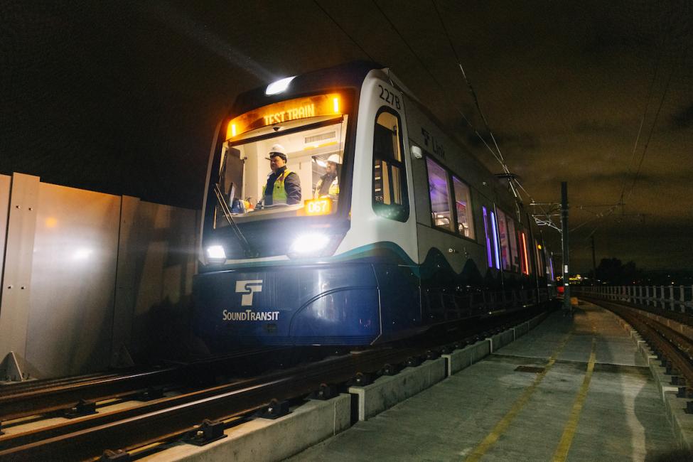 A view of the front of a Link train at night, with the operator visible in the lighted cab