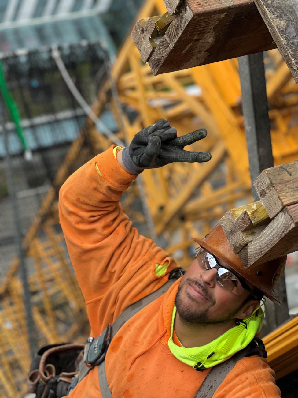 A construction worker gives a peace sign to the camera