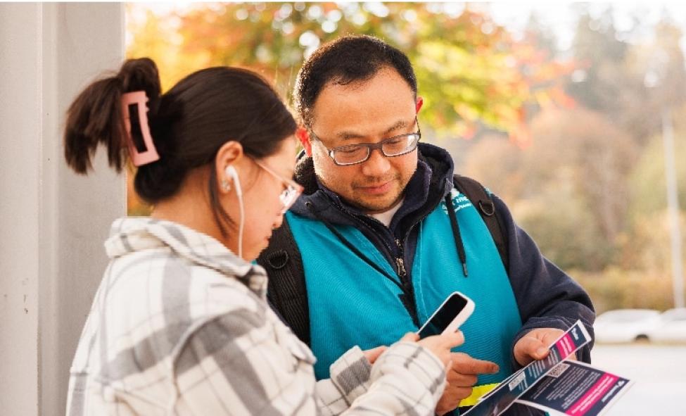 A Sound Transit ambassador shows a passenger how to submit survey feedback at a station.