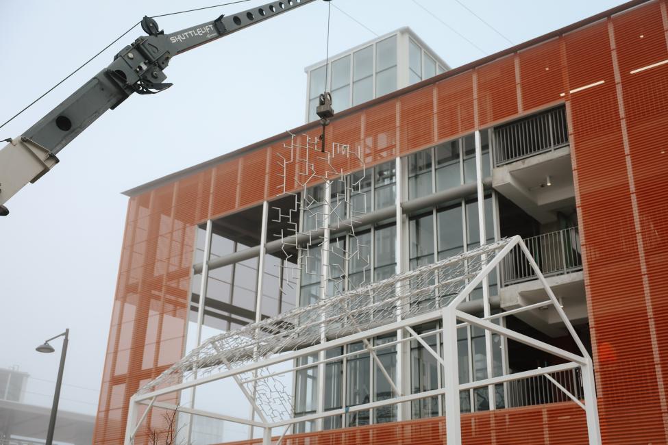 Crane with a piece of the metal sculpture suspended in the air, ready to be placed