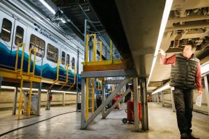 Photo of a worker and a link train on a raised platform at the Operations and Maintenance Facility South