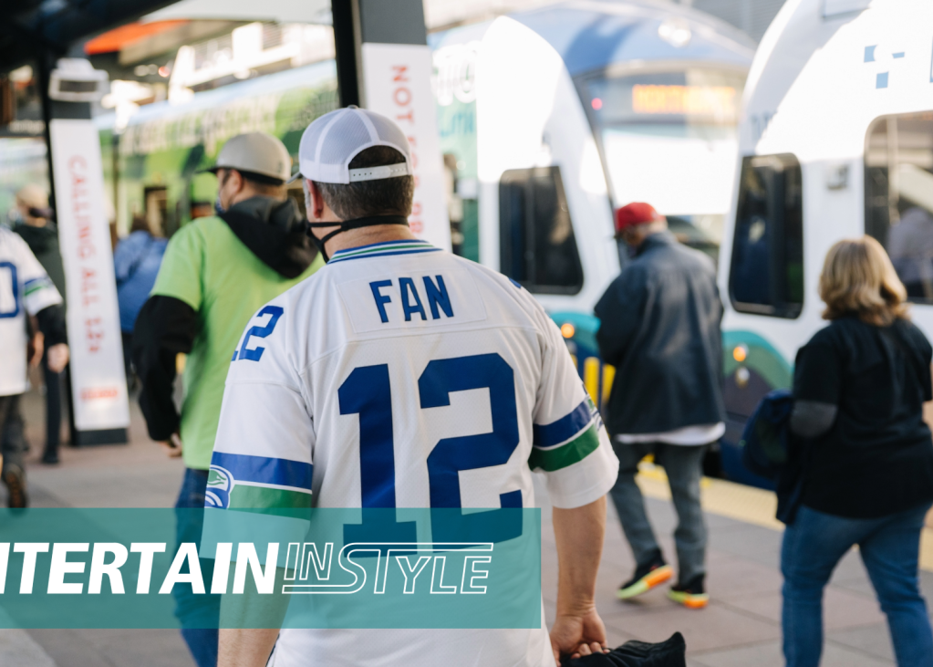 A Seahawks fan walks on a train platform surrounded by other people