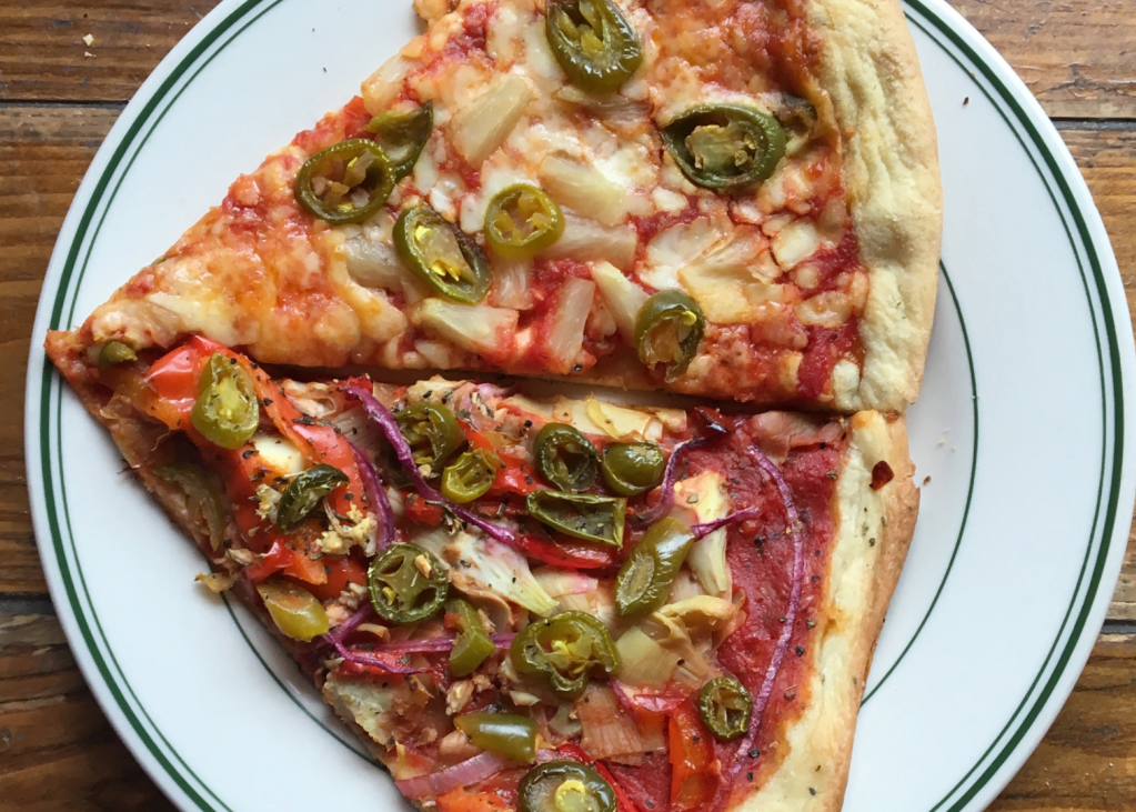 Two slices of pizza on a plate with various toppings, including cheese and peppers